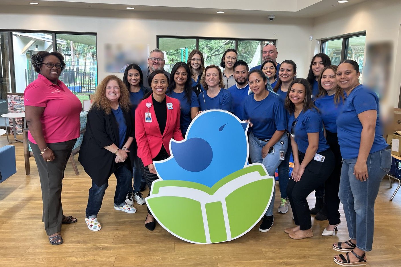Community volunteers gathered around a large West Lakes Early Learning Center logo standee